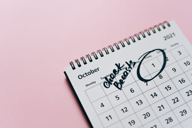 Calendar de perete cu zile bifate cu marker, lângă o cană și o carte