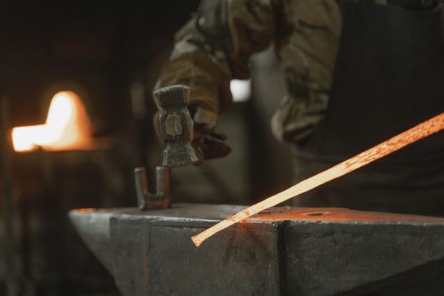 Fierar care modelează pe nicovală o bucată de fier înroșit